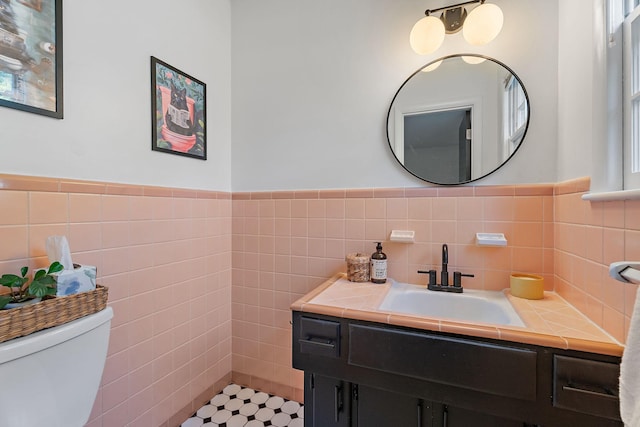 bathroom featuring tile patterned flooring, vanity, toilet, and tile walls