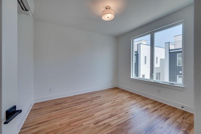 unfurnished room featuring a wall mounted air conditioner and light wood-type flooring