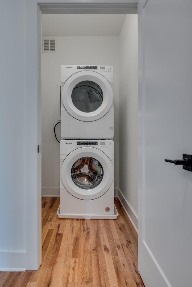 laundry room featuring light wood-type flooring and stacked washing maching and dryer