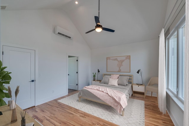 bedroom featuring light wood-type flooring, high vaulted ceiling, an AC wall unit, and ceiling fan