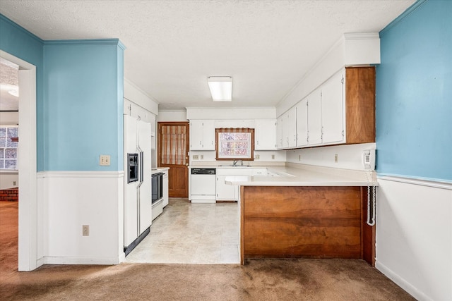 kitchen featuring white appliances, light carpet, white cabinets, ornamental molding, and a textured ceiling