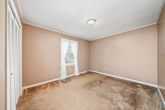 unfurnished bedroom with carpet, ornamental molding, a textured ceiling, and a closet