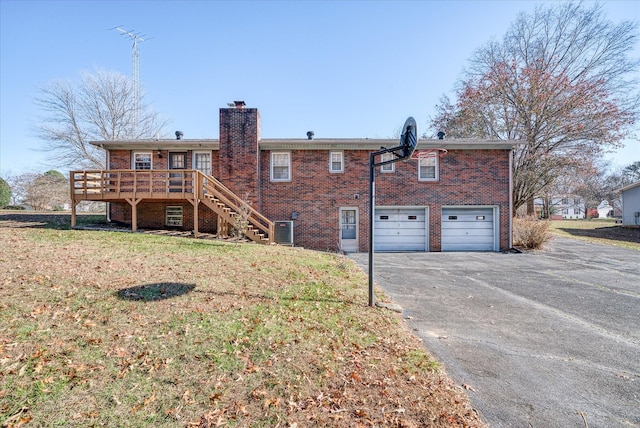 rear view of house with a lawn, a garage, central air condition unit, and a wooden deck