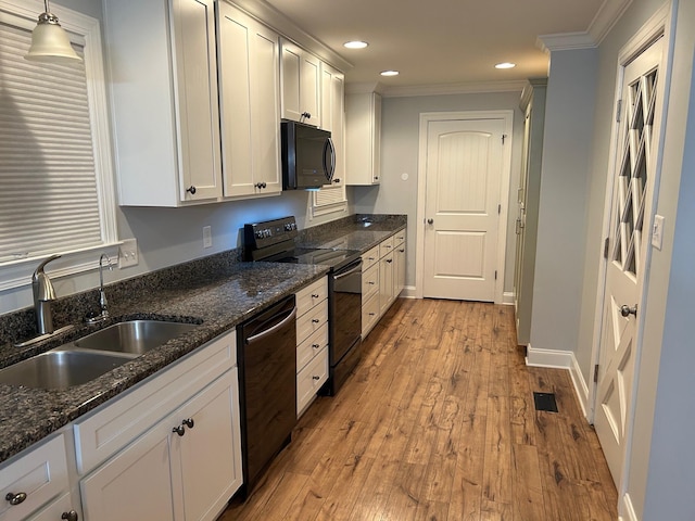 kitchen with sink, appliances with stainless steel finishes, pendant lighting, white cabinets, and light wood-type flooring