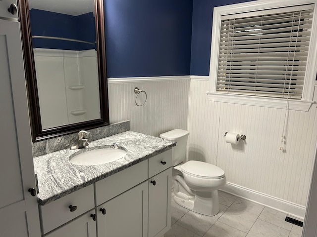 bathroom featuring tile patterned flooring, vanity, toilet, and walk in shower