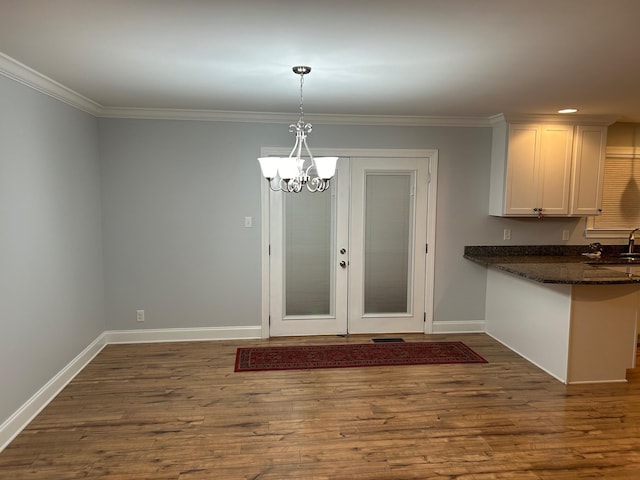 unfurnished dining area featuring crown molding, dark hardwood / wood-style flooring, sink, and a notable chandelier