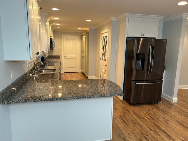 kitchen featuring white cabinets, appliances with stainless steel finishes, light wood-type flooring, and dark stone counters