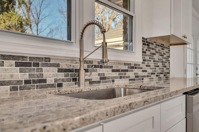 kitchen featuring white cabinetry, light stone countertops, sink, dishwasher, and tasteful backsplash