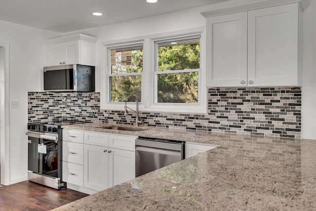 kitchen with light stone countertops, sink, white cabinets, and stainless steel appliances