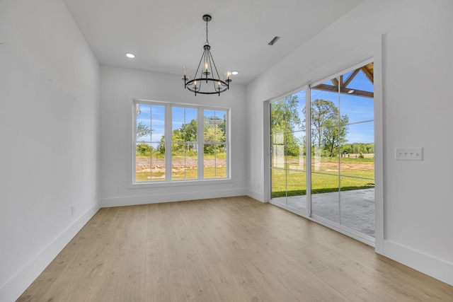 unfurnished dining area featuring a notable chandelier and light wood-type flooring