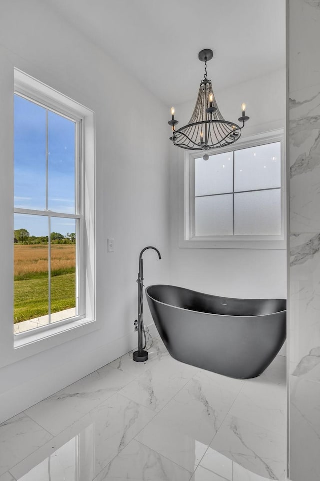 bathroom featuring a chandelier, a wealth of natural light, and a tub