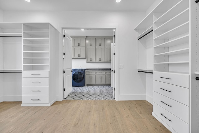 spacious closet with washer / dryer and light hardwood / wood-style flooring