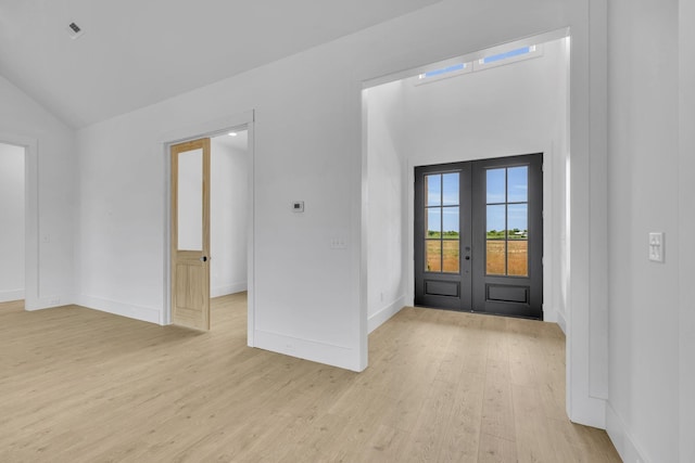 foyer entrance with french doors, light hardwood / wood-style floors, and vaulted ceiling