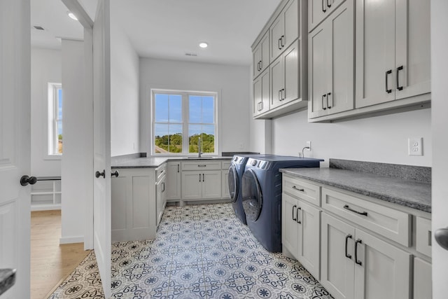 clothes washing area featuring cabinets, independent washer and dryer, and light hardwood / wood-style flooring