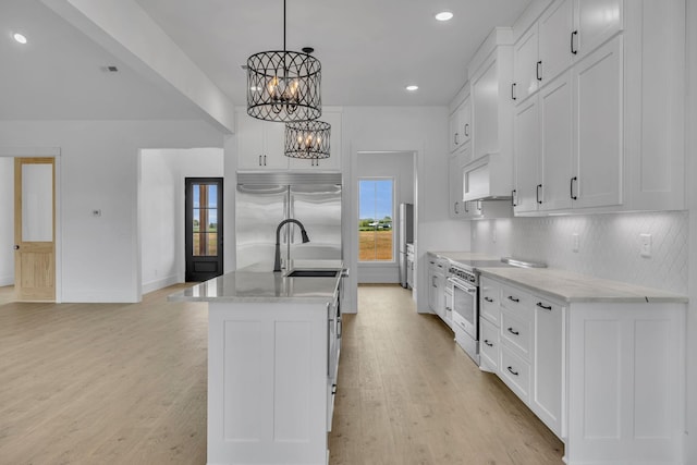 kitchen with pendant lighting, a center island with sink, a notable chandelier, light hardwood / wood-style floors, and white cabinetry