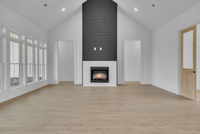 unfurnished living room featuring light hardwood / wood-style floors, a fireplace, and high vaulted ceiling