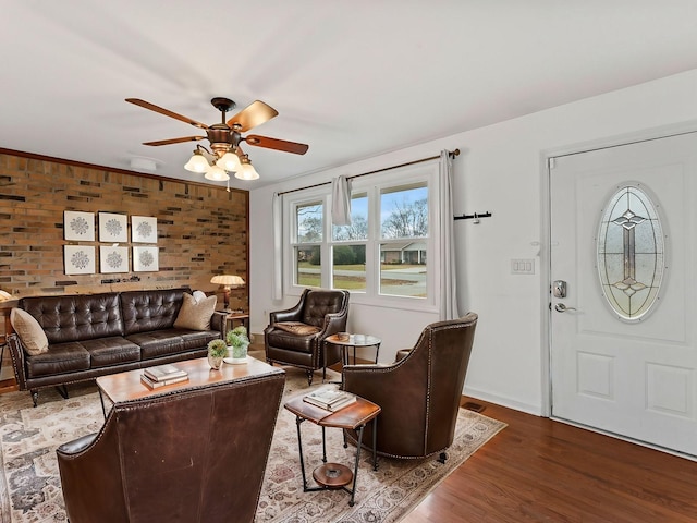 living room with hardwood / wood-style flooring, ceiling fan, and brick wall