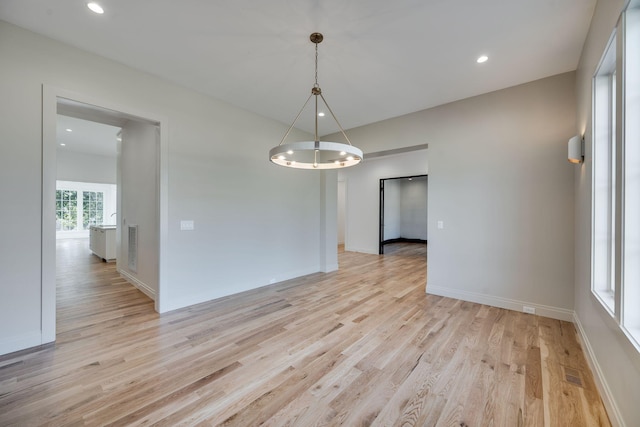 unfurnished dining area featuring an inviting chandelier and light hardwood / wood-style floors