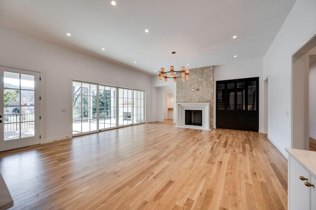 unfurnished living room with a fireplace, light wood-type flooring, and a notable chandelier