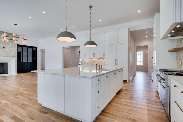 kitchen with white cabinetry, sink, pendant lighting, and a large island with sink