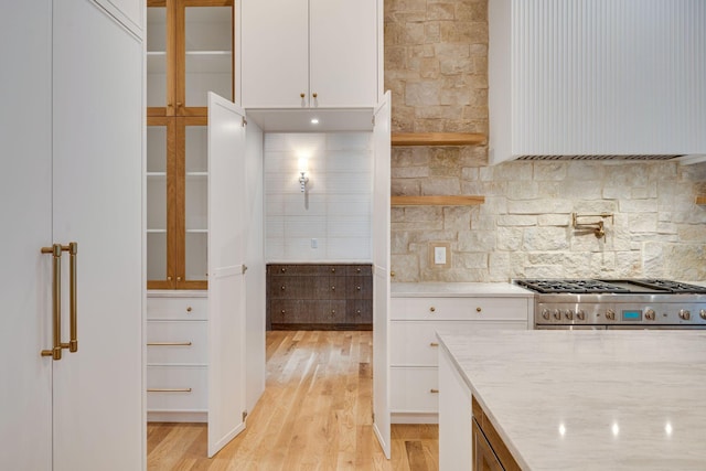 kitchen with white cabinetry, tasteful backsplash, stove, and light wood-type flooring