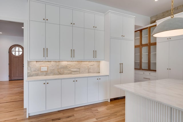 kitchen with white cabinetry, backsplash, and light hardwood / wood-style flooring