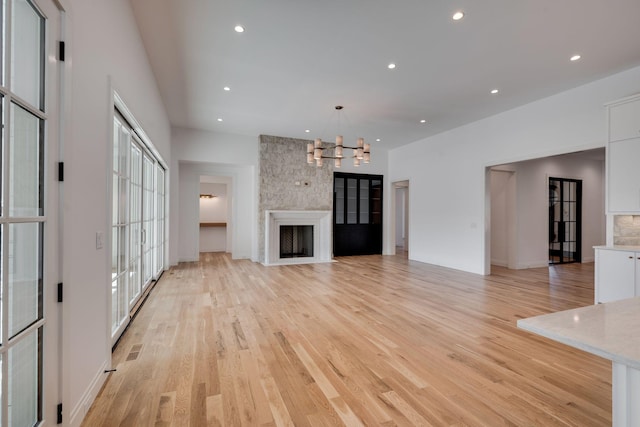 unfurnished living room featuring a large fireplace, a wealth of natural light, and light wood-type flooring