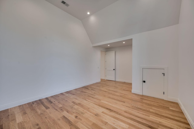 empty room featuring high vaulted ceiling and light hardwood / wood-style flooring