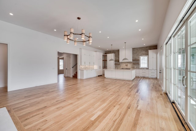 unfurnished living room with an inviting chandelier, a healthy amount of sunlight, and light wood-type flooring