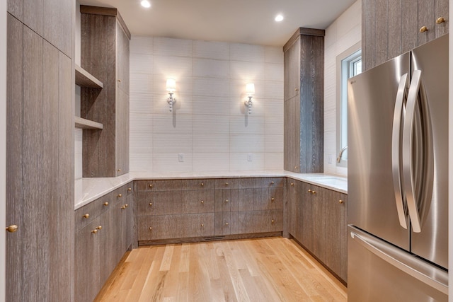 kitchen featuring stainless steel fridge, sink, tile walls, and light wood-type flooring