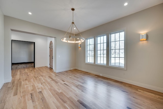 unfurnished dining area with a chandelier and light wood-type flooring