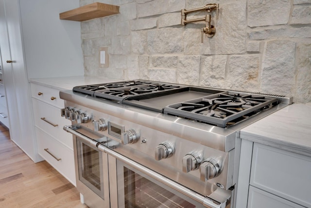 kitchen featuring white cabinetry, double oven range, backsplash, and light wood-type flooring