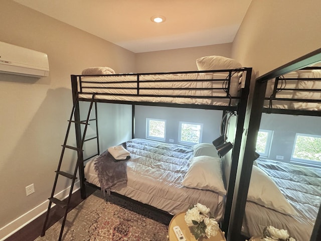 bedroom with a wall unit AC and wood-type flooring