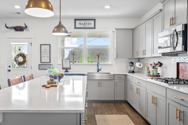 kitchen featuring appliances with stainless steel finishes, a center island, dark hardwood / wood-style floors, and sink