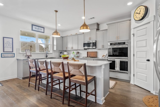 kitchen with appliances with stainless steel finishes, a center island, gray cabinets, and dark hardwood / wood-style floors