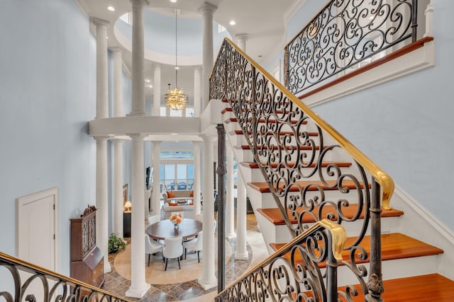 stairway with a chandelier, ornate columns, and a towering ceiling