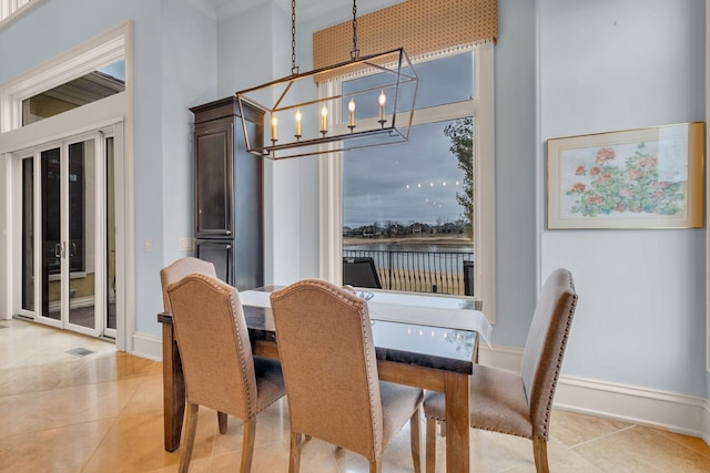 tiled dining area featuring a high ceiling and a notable chandelier