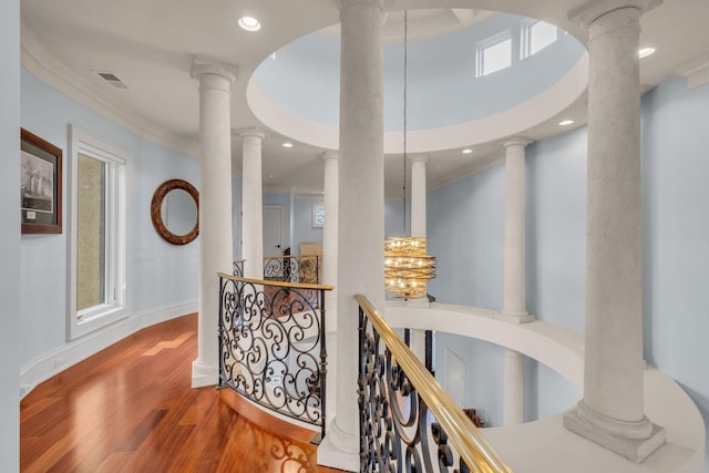 hall featuring crown molding, ornate columns, and wood-type flooring