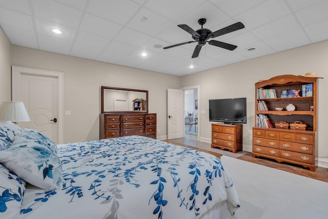 tiled bedroom with ceiling fan and a drop ceiling