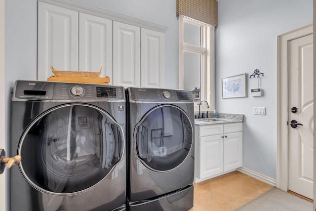 clothes washing area featuring light tile patterned floors, sink, separate washer and dryer, and cabinets