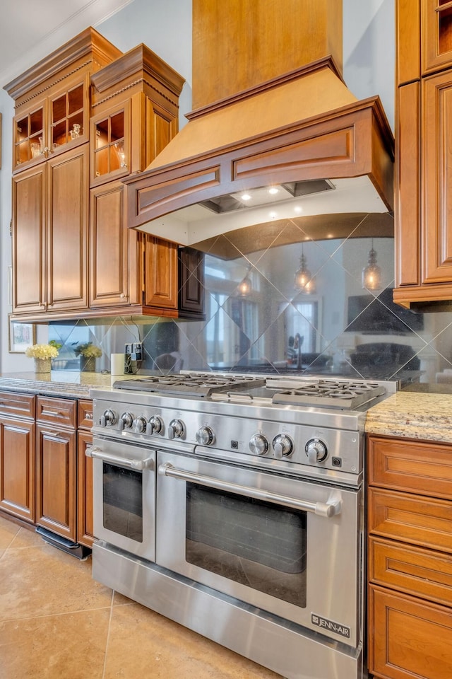 kitchen featuring range with two ovens, light stone counters, custom range hood, backsplash, and light tile patterned floors