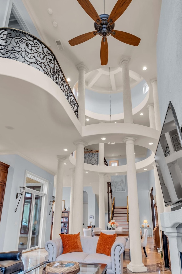 living room with ceiling fan, ornate columns, and a high ceiling