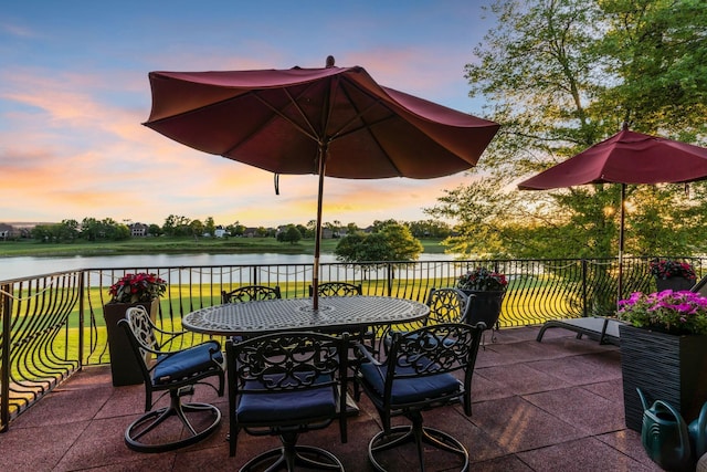 patio terrace at dusk featuring a water view