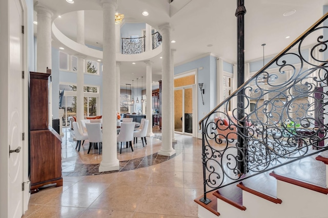 entryway featuring light tile patterned floors, decorative columns, and a high ceiling