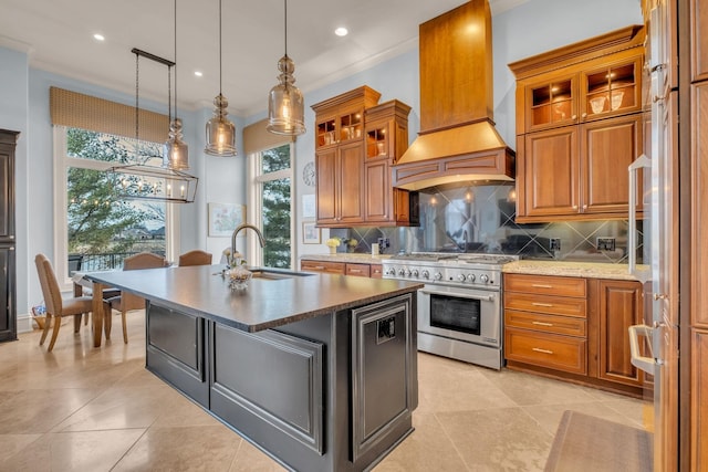 kitchen featuring an island with sink, decorative light fixtures, high end stainless steel range, premium range hood, and sink