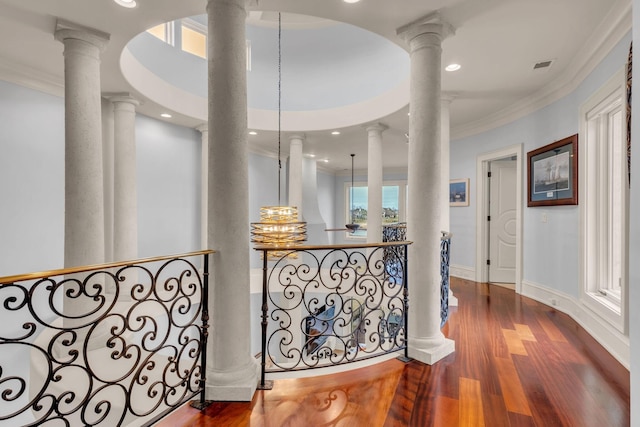 hall with hardwood / wood-style flooring, crown molding, and decorative columns