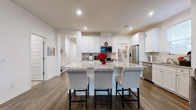 kitchen featuring white cabinets, appliances with stainless steel finishes, tasteful backsplash, a kitchen island, and dark hardwood / wood-style flooring