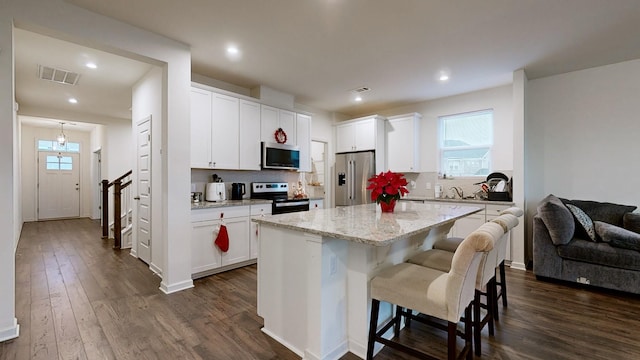 kitchen with decorative backsplash, stainless steel appliances, dark wood-type flooring, white cabinetry, and a kitchen island