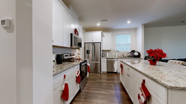 kitchen featuring white cabinetry, dark wood-type flooring, stainless steel appliances, decorative backsplash, and a kitchen island