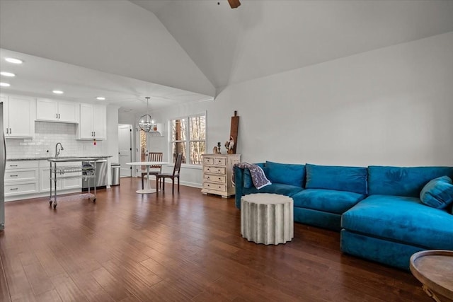 living room featuring sink, dark hardwood / wood-style flooring, lofted ceiling, and a notable chandelier